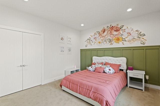 bedroom featuring recessed lighting, a closet, light colored carpet, and a decorative wall