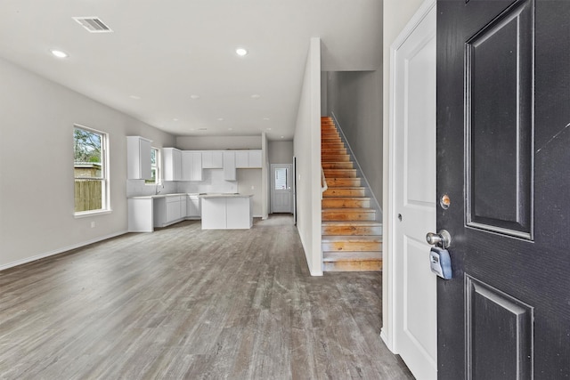 unfurnished living room featuring recessed lighting, visible vents, stairway, and light wood finished floors