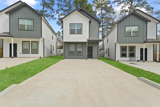 view of front of house with a patio area, a front yard, board and batten siding, and roof with shingles