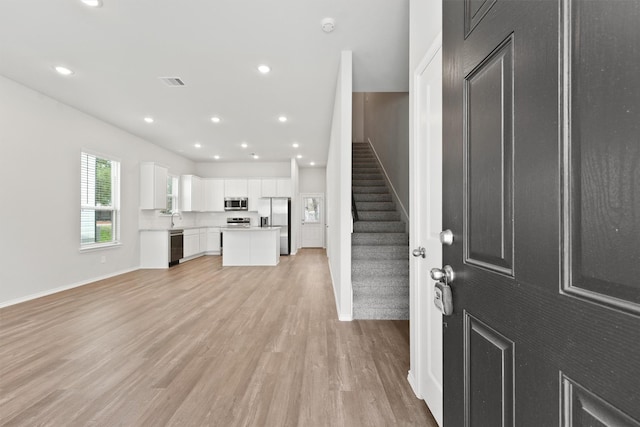 foyer with recessed lighting, visible vents, light wood-style floors, baseboards, and stairs