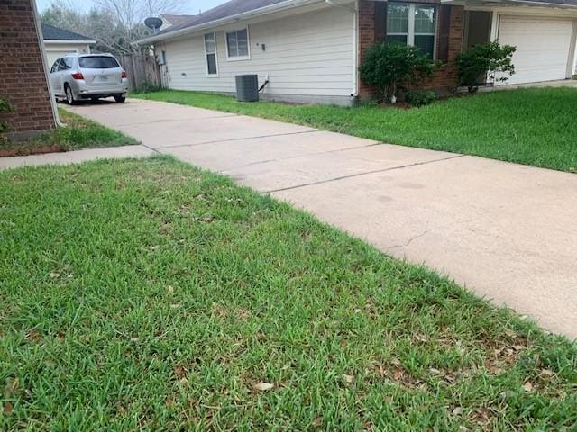 view of side of home with brick siding, central air condition unit, concrete driveway, a lawn, and an attached garage