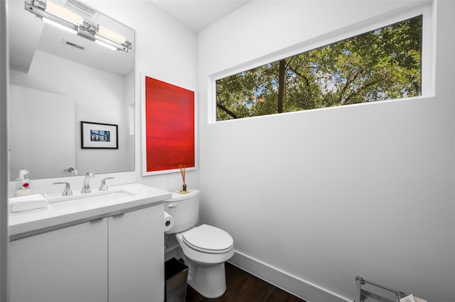 bathroom featuring toilet, wood finished floors, vanity, visible vents, and baseboards