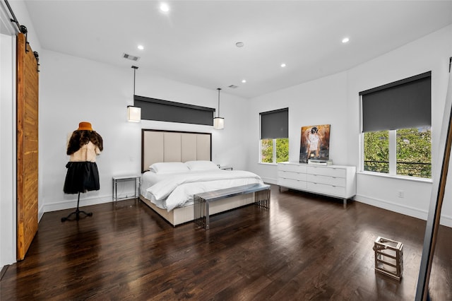 bedroom with recessed lighting, visible vents, a barn door, wood finished floors, and baseboards