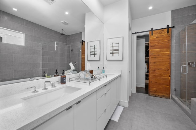 bathroom featuring double vanity, a shower stall, a walk in closet, and a sink