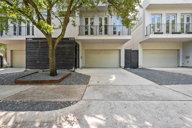 view of front facade with french doors, driveway, an attached garage, and stucco siding