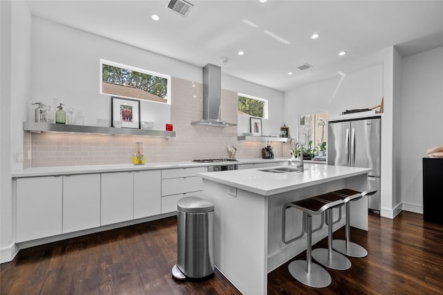 kitchen with visible vents, appliances with stainless steel finishes, a sink, wall chimney range hood, and modern cabinets