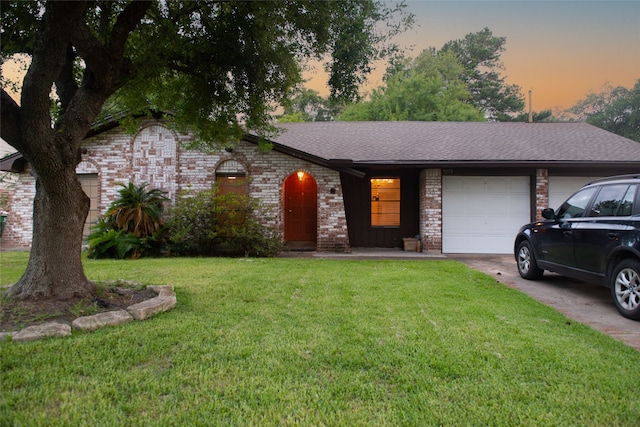 single story home featuring driveway, a garage, a shingled roof, a front lawn, and brick siding