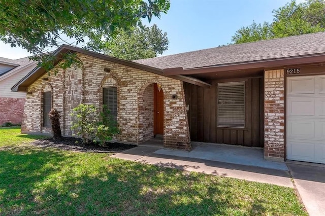 doorway to property with a garage, brick siding, a yard, and a shingled roof