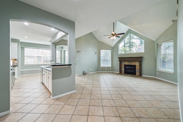 kitchen featuring a tiled fireplace, light tile patterned flooring, white cabinetry, and ceiling fan