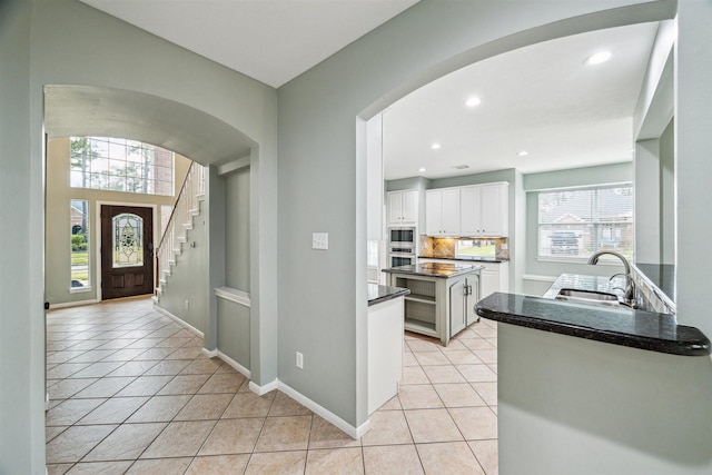 entrance foyer featuring recessed lighting, baseboards, arched walkways, and light tile patterned flooring