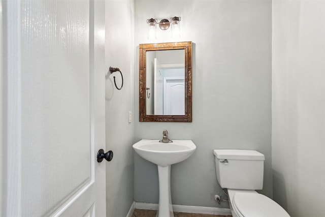 half bathroom featuring toilet and baseboards