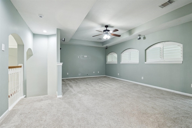 unfurnished room with visible vents, baseboards, carpet floors, a raised ceiling, and a ceiling fan