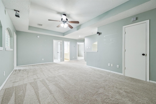 carpeted empty room featuring a tray ceiling, baseboards, a textured ceiling, and visible vents