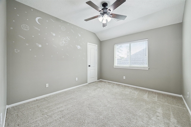 carpeted spare room featuring a textured ceiling, a ceiling fan, baseboards, and vaulted ceiling