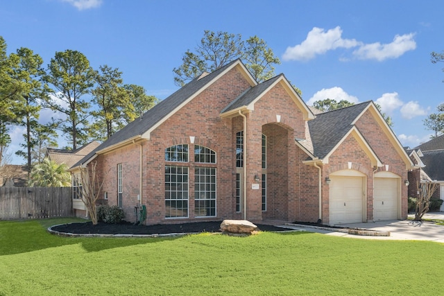 traditional-style home featuring brick siding, an attached garage, a front yard, and fence