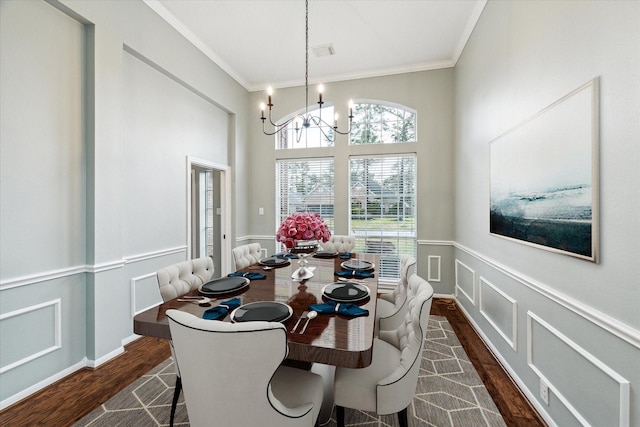 dining area with crown molding, an inviting chandelier, dark wood-style flooring, and a decorative wall