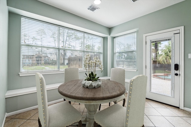 dining area featuring light tile patterned floors, baseboards, visible vents, and a wealth of natural light