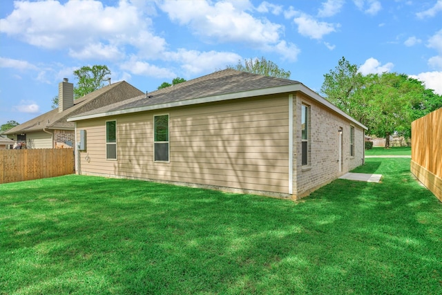 rear view of house with brick siding, a lawn, and fence