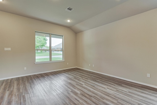 empty room featuring visible vents, baseboards, wood finished floors, and vaulted ceiling