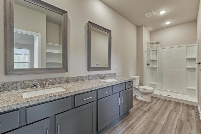 full bath featuring toilet, wood finished floors, a shower stall, and a sink