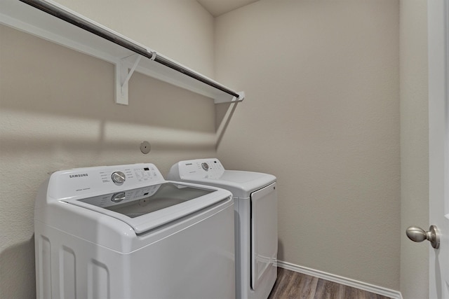 clothes washing area featuring dark wood finished floors, baseboards, washing machine and dryer, and laundry area