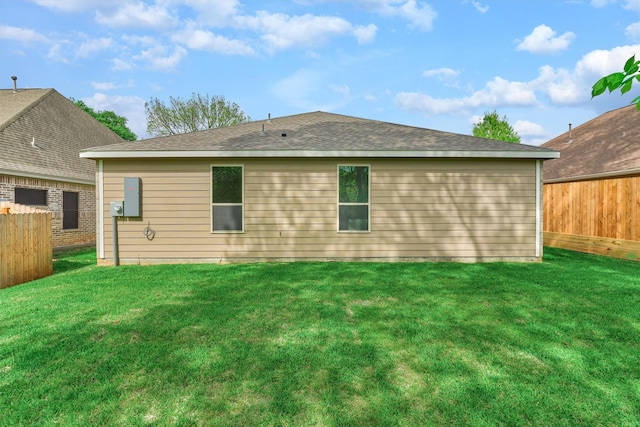 rear view of property featuring a lawn and a fenced backyard