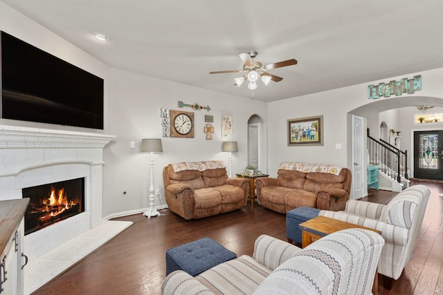 living room featuring arched walkways, a premium fireplace, and hardwood / wood-style flooring