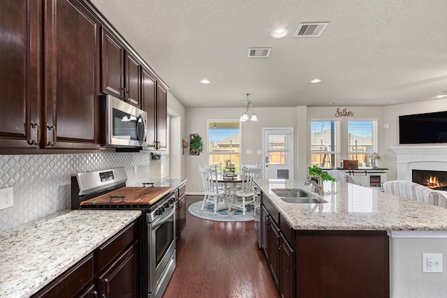 kitchen with dark wood-style floors, stainless steel appliances, visible vents, open floor plan, and a sink