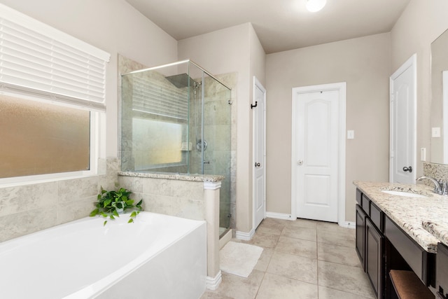 bathroom featuring tile patterned flooring, vanity, baseboards, a shower stall, and a bath