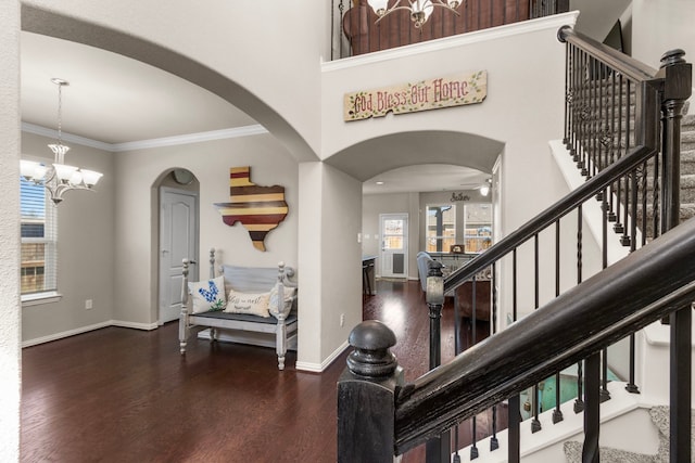 entryway featuring arched walkways, stairway, wood finished floors, and crown molding