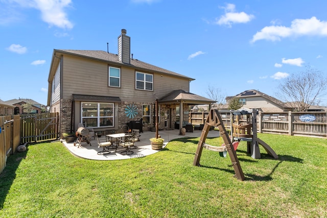 rear view of property featuring a patio, a fenced backyard, a chimney, a yard, and brick siding