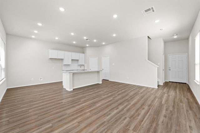 unfurnished living room with recessed lighting, a sink, visible vents, baseboards, and light wood finished floors