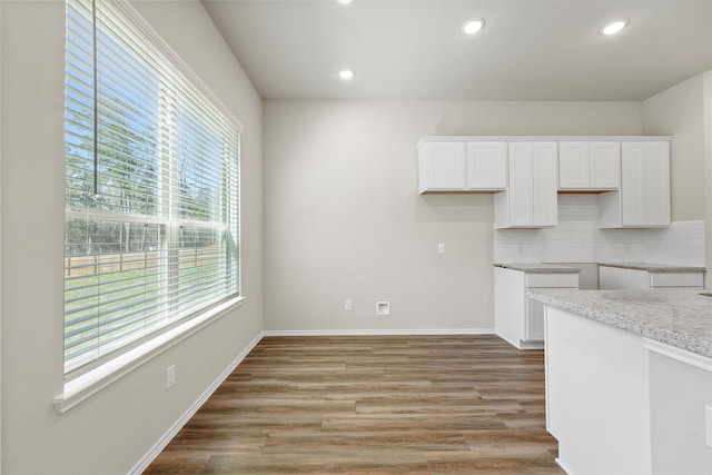 kitchen featuring light wood-type flooring, baseboards, white cabinets, and decorative backsplash