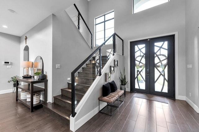 foyer entrance with baseboards, wood finished floors, a high ceiling, stairs, and french doors