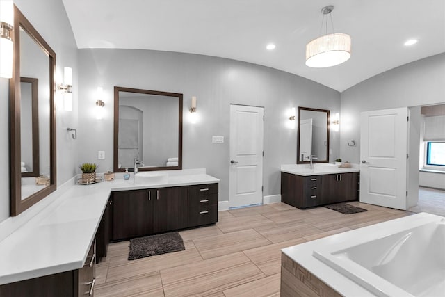 full bath featuring a relaxing tiled tub, lofted ceiling, a sink, two vanities, and recessed lighting