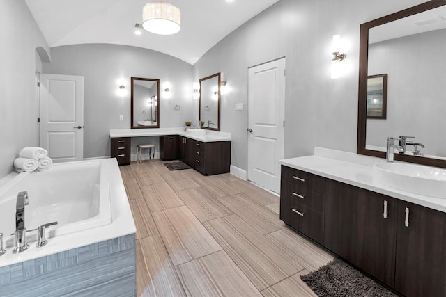 bathroom featuring two vanities, a sink, vaulted ceiling, a bath, and wood tiled floor