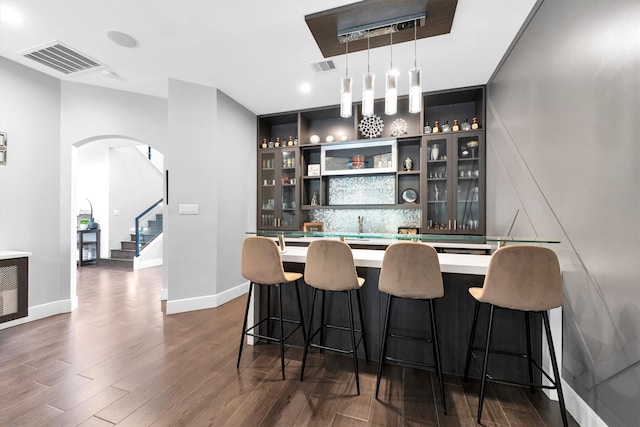 bar featuring stairway, dark wood-style flooring, indoor wet bar, and visible vents