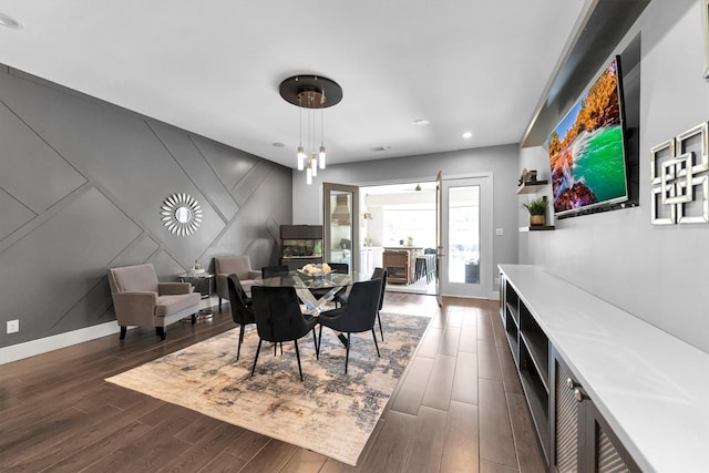 dining space with a decorative wall, recessed lighting, an accent wall, baseboards, and dark wood finished floors