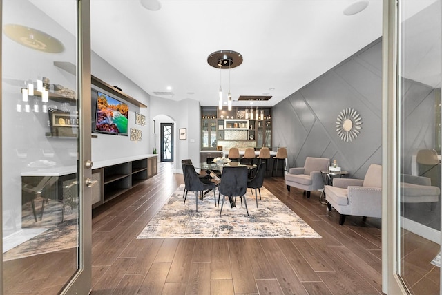 dining area with dark wood-style floors and arched walkways