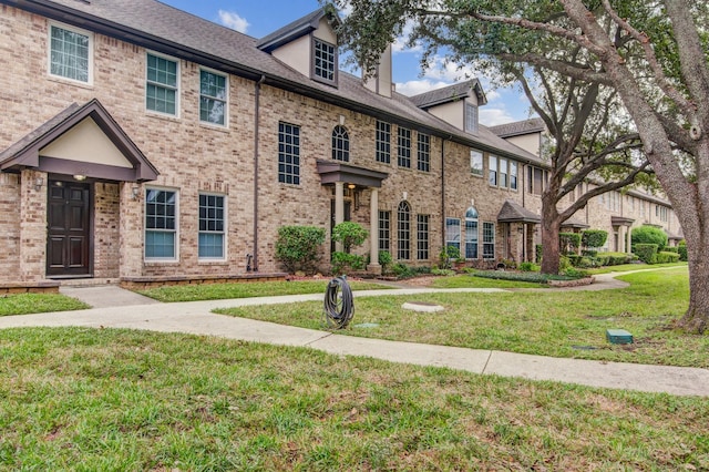 view of property featuring brick siding and a front lawn