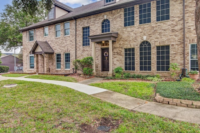 view of front facade with brick siding and a front lawn