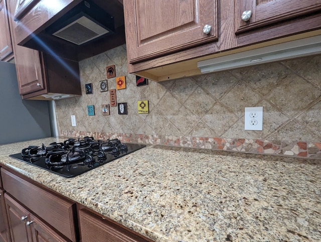 kitchen featuring black gas cooktop, light stone counters, exhaust hood, and decorative backsplash