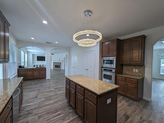 kitchen featuring dark brown cabinetry, dark wood-style floors, appliances with stainless steel finishes, an inviting chandelier, and backsplash