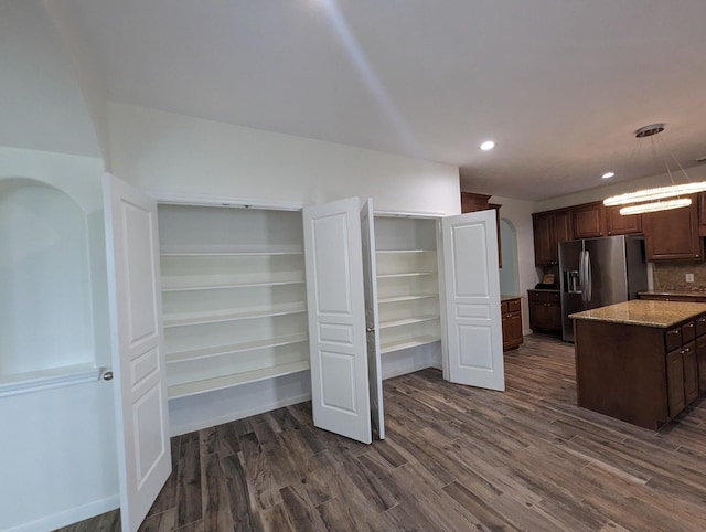 interior space featuring dark wood-type flooring, recessed lighting, decorative light fixtures, and stainless steel fridge with ice dispenser