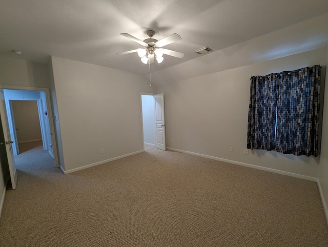 interior space featuring baseboards, visible vents, ceiling fan, and light colored carpet