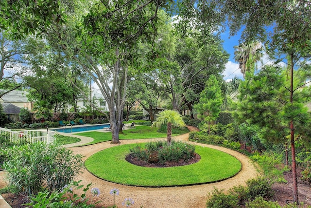 surrounding community with a swimming pool, fence, and a lawn