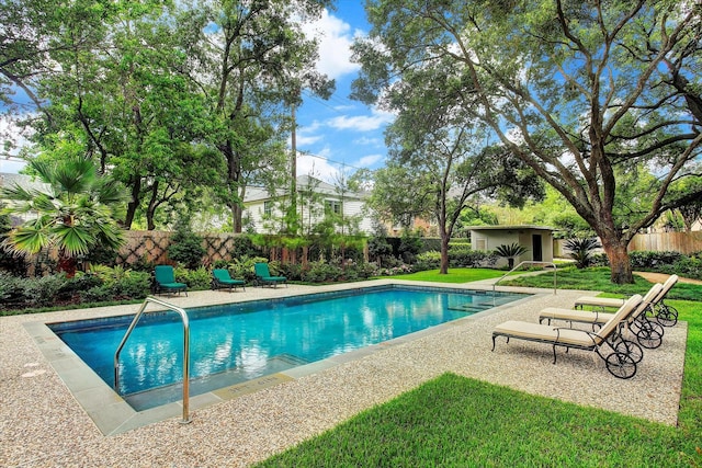 view of swimming pool with a fenced in pool, an outbuilding, fence private yard, a yard, and a patio area