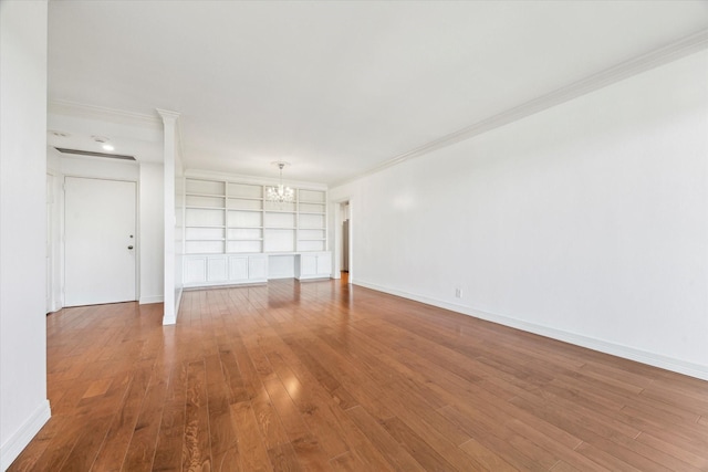 unfurnished room with baseboards, crown molding, a chandelier, and wood finished floors