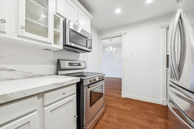 kitchen featuring white cabinets, light wood-style floors, ornamental molding, appliances with stainless steel finishes, and glass insert cabinets