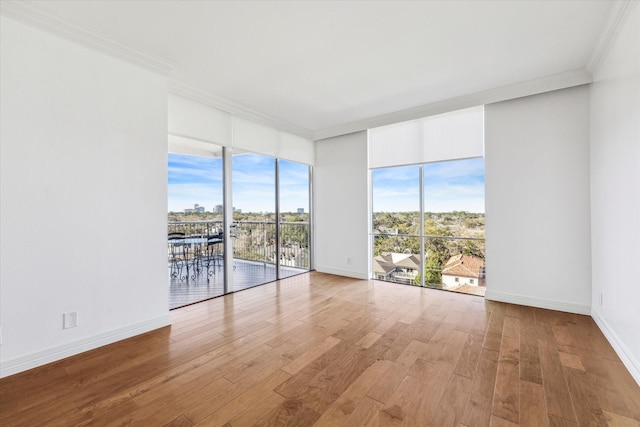 unfurnished room featuring ornamental molding, baseboards, and wood finished floors